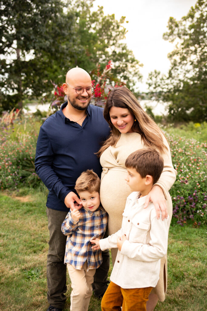 family with boys expecting baby during fall family photo session near wildflowers