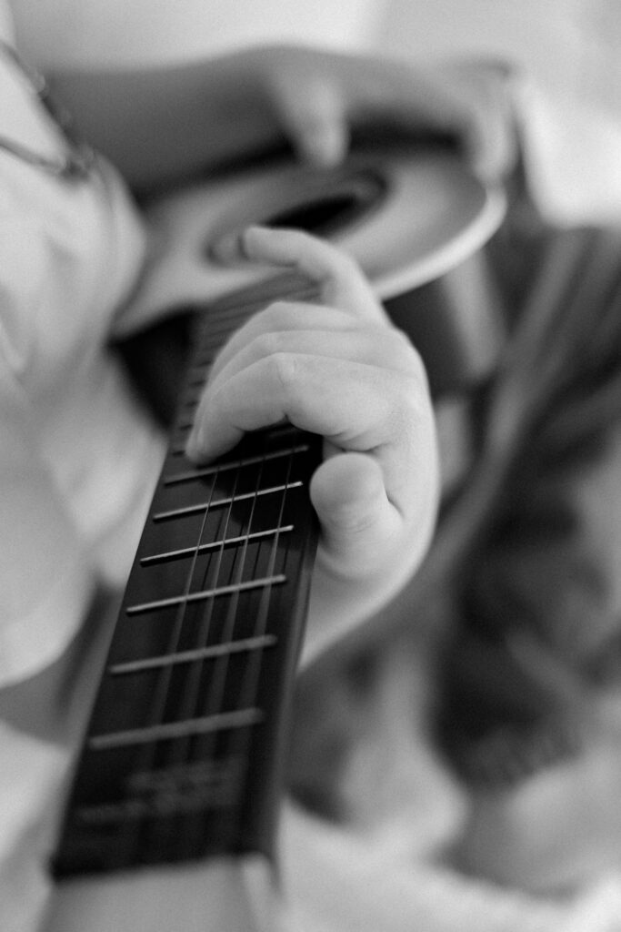 young boy hand playing guitar during photo session