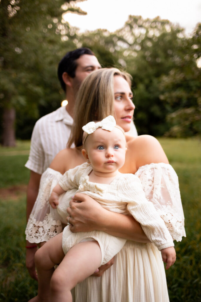 mother father and one year old daughter in park during milestone family session