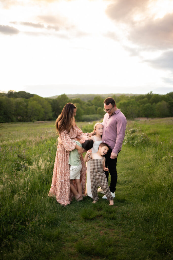 family of five standing in a field at golden hour during photo session