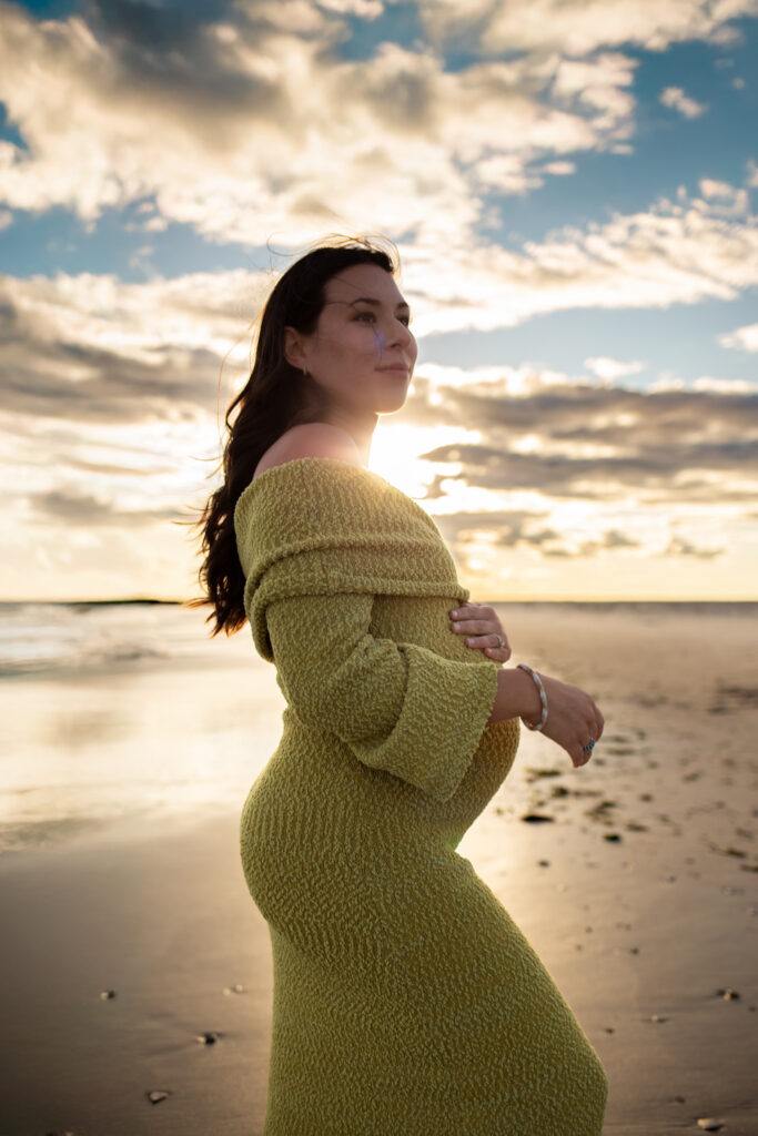 expecting mama at point lookout beach looking off at family during maternity photography session