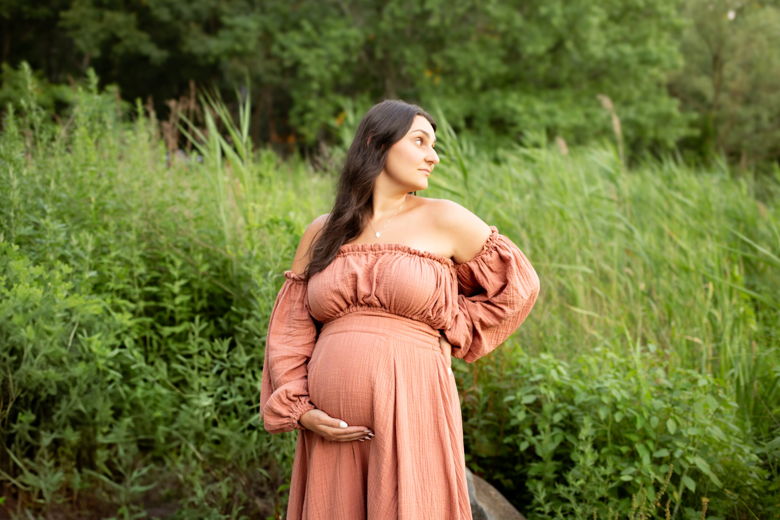 pregnant woman during maternity photography session holding belly in field of flowers